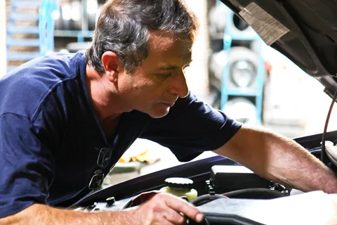 Monteur van Auto Weber aan het werk onder de motorkap in de werkplaats