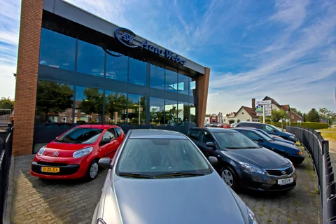 Het pand van Auto Weber aan de Schoolstraat in Echt, met de glazen showroom en auto's ervoor